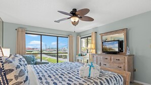 Camera d'albergo con un letto grande, una ventola a soffitto, una TV e vista sulla città.