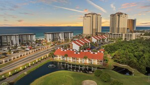 Un hotel sulla costa con diversi edifici alti, un campo da golf e un porto turistico.