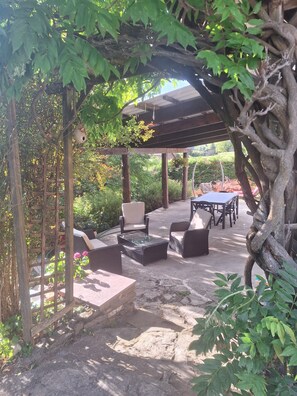 An outdoor patio area with wicker furniture, a pergola, and a stone pathway.