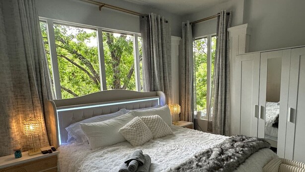 Une chambre avec un grand lit, une armoire et une fenêtre avec des rideaux.