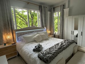 A bedroom with a large bed, a wardrobe, and a window with curtains.