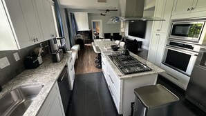 Une cuisine moderne dotée de plans de travail en granit, d’appareils électroménagers en acier inoxydable et d’un îlot central.