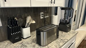 Une cuisine équipée d’un grille-pain, d’un mixeur et d’un bloc à couteaux sur le plan de travail.