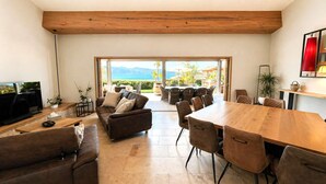 Un'ampia zona giorno con un grande tavolo in legno, posti a sedere confortevoli e vista sull'esterno.