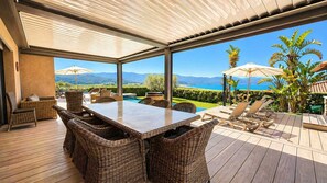 A covered outdoor area with a dining table and chairs, a pool, and lounge chairs. - Villa Riposu  Jacuzzi  Pool Beach Access on Foot (Sagone)