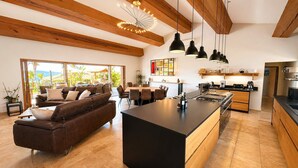 Una cucina moderna con isola centrale, travi in legno e luci a sospensione.