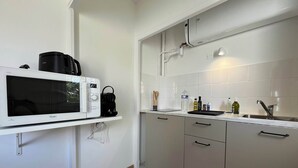 A kitchen with a microwave, kettle, and various kitchen items on the counter.