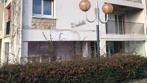 A two-story building with a white facade, a visible balcony on the upper floor, and a sign that reads "L'ostalet".