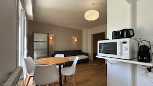 A modern kitchen with a dining table, chairs, a refrigerator, a microwave, and a coffee machine.