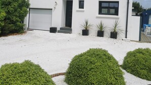 A white two-story house with a garage, a small porch, and a gravel driveway. - Large, quiet house, large garden, heated swimming pool, ideal for families (La Baule-Escoublac)