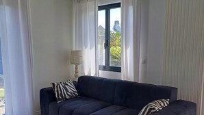 A modern living room with a dark blue sofa, a white coffee table, and a patterned lamp. - Large, quiet house, large garden, heated swimming pool, ideal for families (La Baule-Escoublac)
