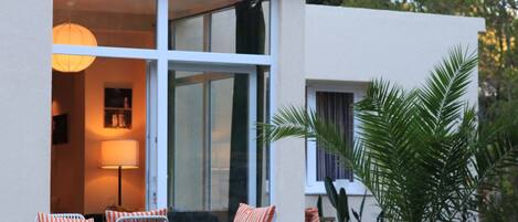 A modern building with a patio area featuring outdoor seating and a lamp.