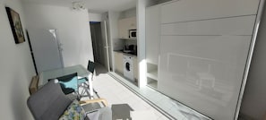 A compact living space with a dining area, a washing machine, and a wardrobe.