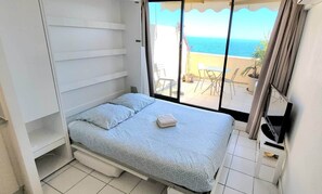 A bedroom with a bed, a small table, and a view of the sea. - "Theo'z Top Floor & Sea View" (Cannes)