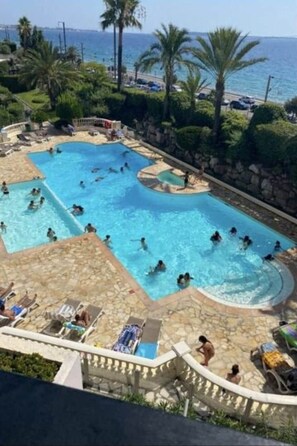 A swimming pool area with multiple pools, lounge chairs, and palm trees. - "Theo'z Top Floor & Sea View" (Cannes)