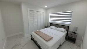 A bedroom with a bed, nightstands, a wardrobe, and a window with blinds. - 3-bedroom house in welcoming Temple Terrace, WiFi. EV car charging oulet, PS4 (Temple Terrace)