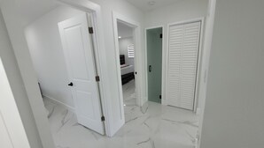 A hallway with white doors, a marble floor, and a closet with sliding doors. - 3-bedroom house in welcoming Temple Terrace, WiFi. EV car charging oulet, PS4 (Temple Terrace)