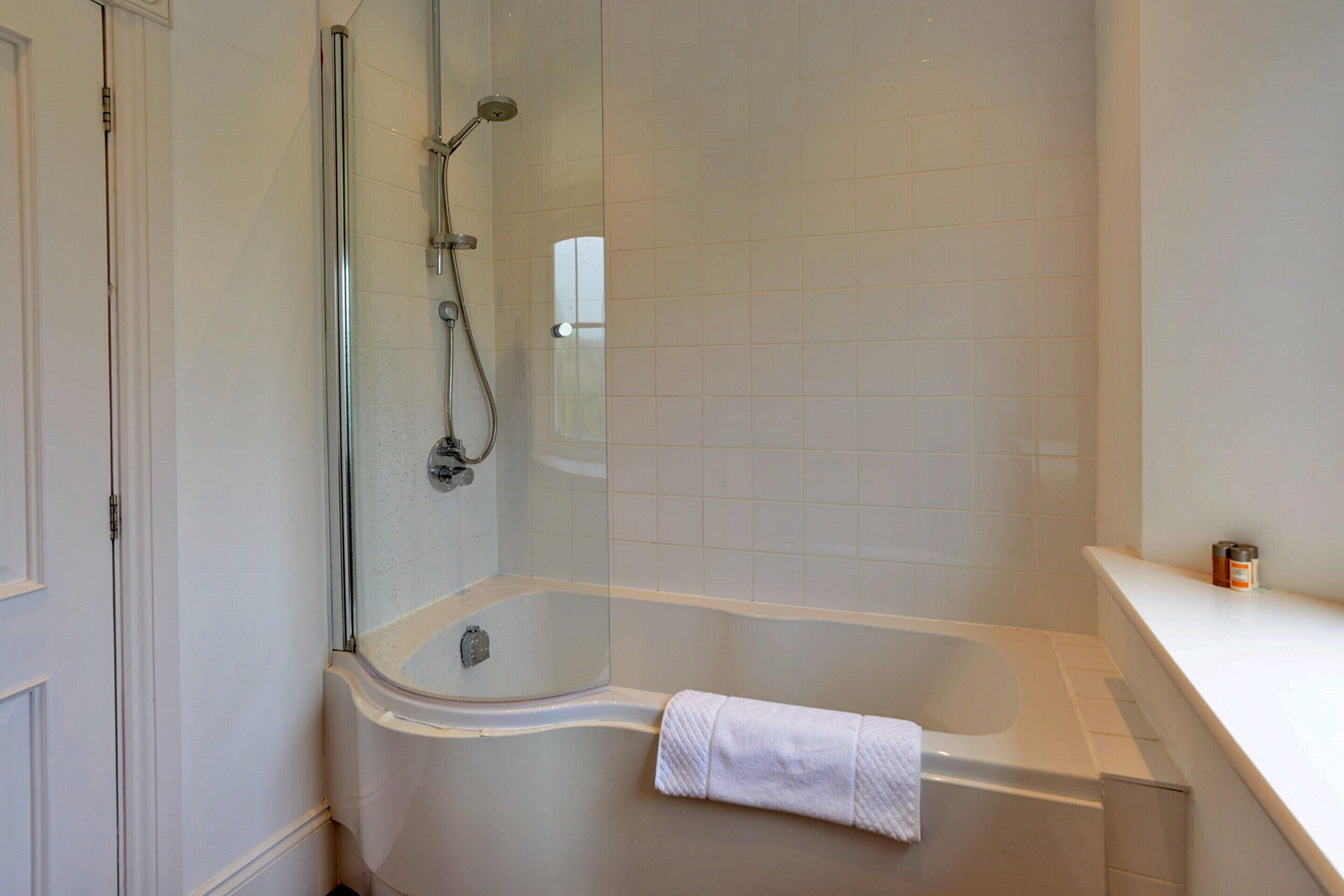Un baño moderno con ducha de vidrio, una bañera independiente y un revestimiento de azulejos blancos.