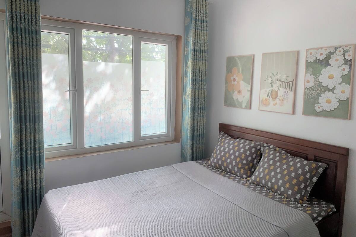 Ein Schlafzimmer mit einem Bett, Vorhängen und drei Blumenbildern.