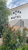 Placa do motel 'IMADA MOTEL', com uma parede de pedra e uma escadaria.