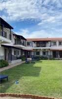 Um pátio com gramado, um banco azul e uma pequena mesa.