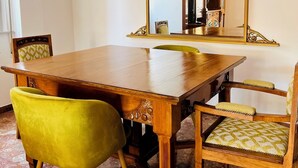 A dining area with a wooden table, four chairs, and a large mirror with an ornate frame.