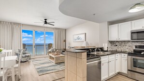 Una cocina moderna con armarios blancos, encimera negra y vistas al exterior.