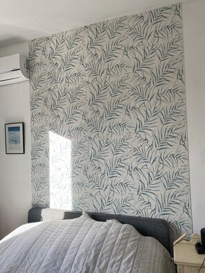 Relax in a cozy space with a large bed and a unique bamboo leaf pattern wallpaper.