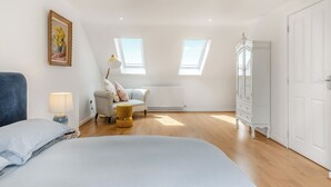 A bedroom with a bed, a chair, a lamp, a wardrobe, and two skylights. - 2 bedroom accommodation in Seaford (Seaford)