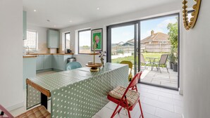 A modern kitchen with a dining area, large windows, and a view of the backyard. - 2 bedroom accommodation in Seaford (Seaford)