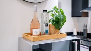A kitchen counter with a tray holding a wine bottle, a water bottle, and a potted plant. - Newly Converted 2BDR 1BA APT in Hounslow (Hounslow)