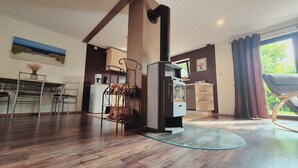 A modern kitchen with a central island, a dining area with metal chairs, a built-in oven, and a large window with curtains. - Vacation home in Lieper Winkel (Rankwitz)