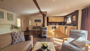 A spacious living room with a sofa, a coffee table with flowers, and a kitchen in the background. - Vacation home in Lieper Winkel (Rankwitz)