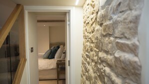 Een slaapkamer met een bed, een nachtkastje en een houten trap die naar een verdieping leidt.