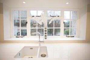 Un baño con un lavamanos blanco, una ventana con múltiples divisiones y vistas al exterior.