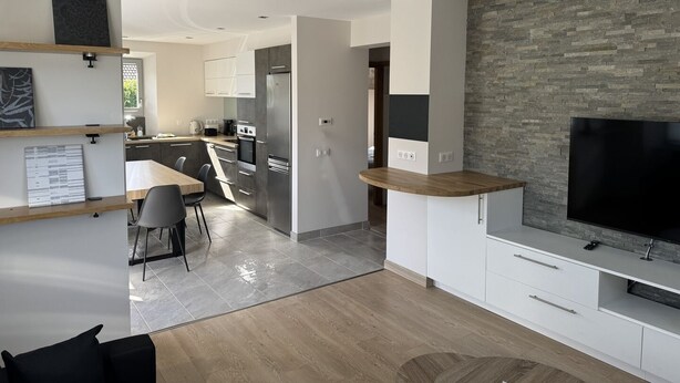 A modern kitchen with a dining area, a TV, and a stone accent wall. - "LA SAUFFAZ - Your vacation in Savoie with family or friends (Faverges)