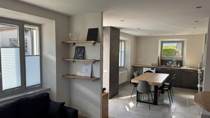 A modern apartment with a dining area, kitchen, and a black sofa. - "LA SAUFFAZ - Your vacation in Savoie with family or friends (Faverges)