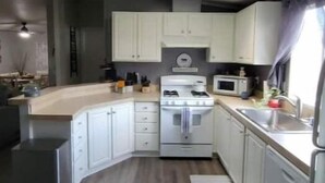 A compact kitchen with white cabinets, a microwave, and a stove.