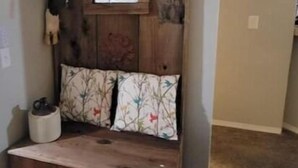 A rustic wooden bench with a decorative headboard, a small window, and a wall-mounted light fixture.