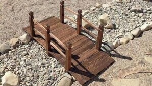 A wooden deck with a stone pathway and a fenced area.