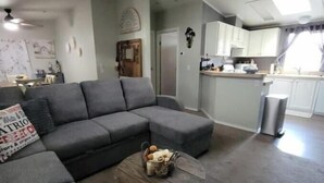 A living room with a grey sectional sofa, a round coffee table with decorative items, and a patterned throw blanket.