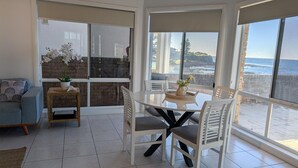 A balcony with a dining table and chairs, a sofa, and a small table with a plant. - Sea Breeze @ Barrack Point (Barrack Point)