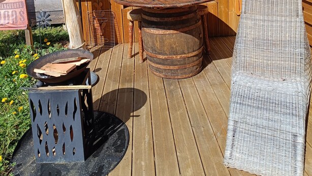 A rustic outdoor seating area with a round wooden table, a wicker chair, and a wooden barrel. - P'tit ranch SPA PRIVATIF Ô Rêves Atypiques (Boucé)