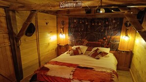 A rustic room with a bed, wooden walls, and a 'Cowboy Way' sign. - P'tit ranch SPA PRIVATIF Ô Rêves Atypiques (Boucé)