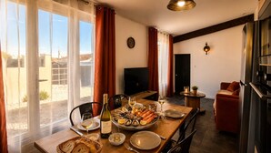 A dining area with a table set for a meal, a television in the background, and a view of the outdoors.