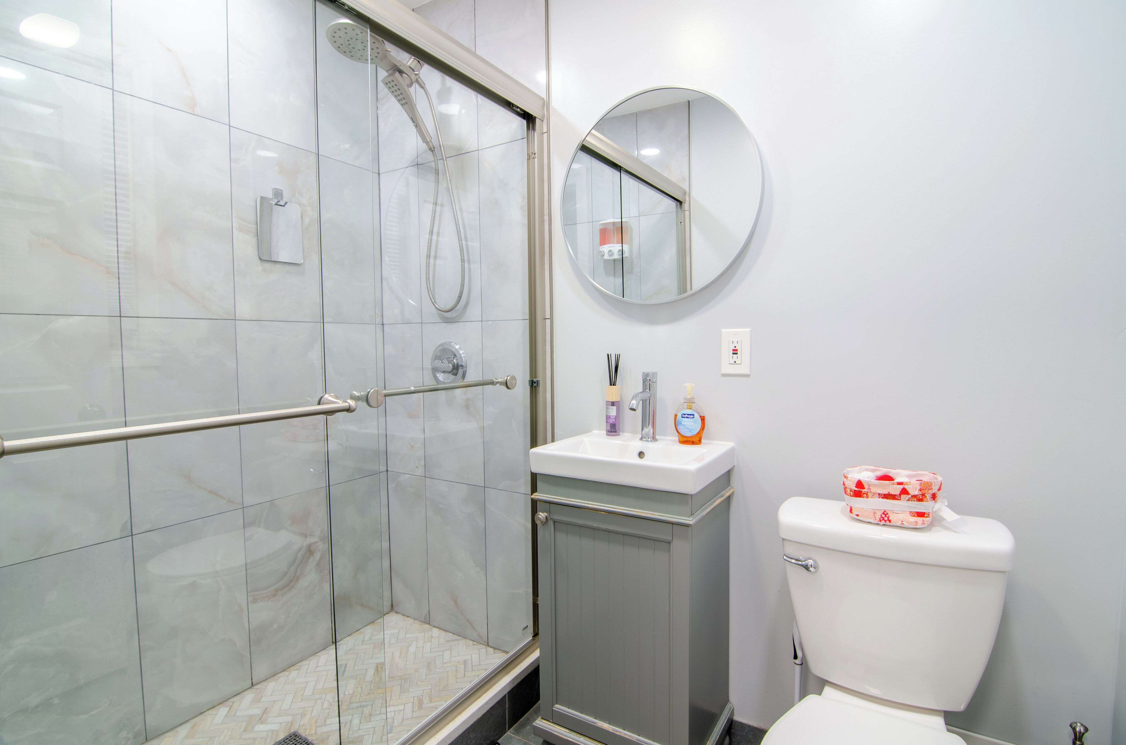 Une salle de bain avec une douche à parois de verre, un lavabo avec des articles de toilette et des toilettes.