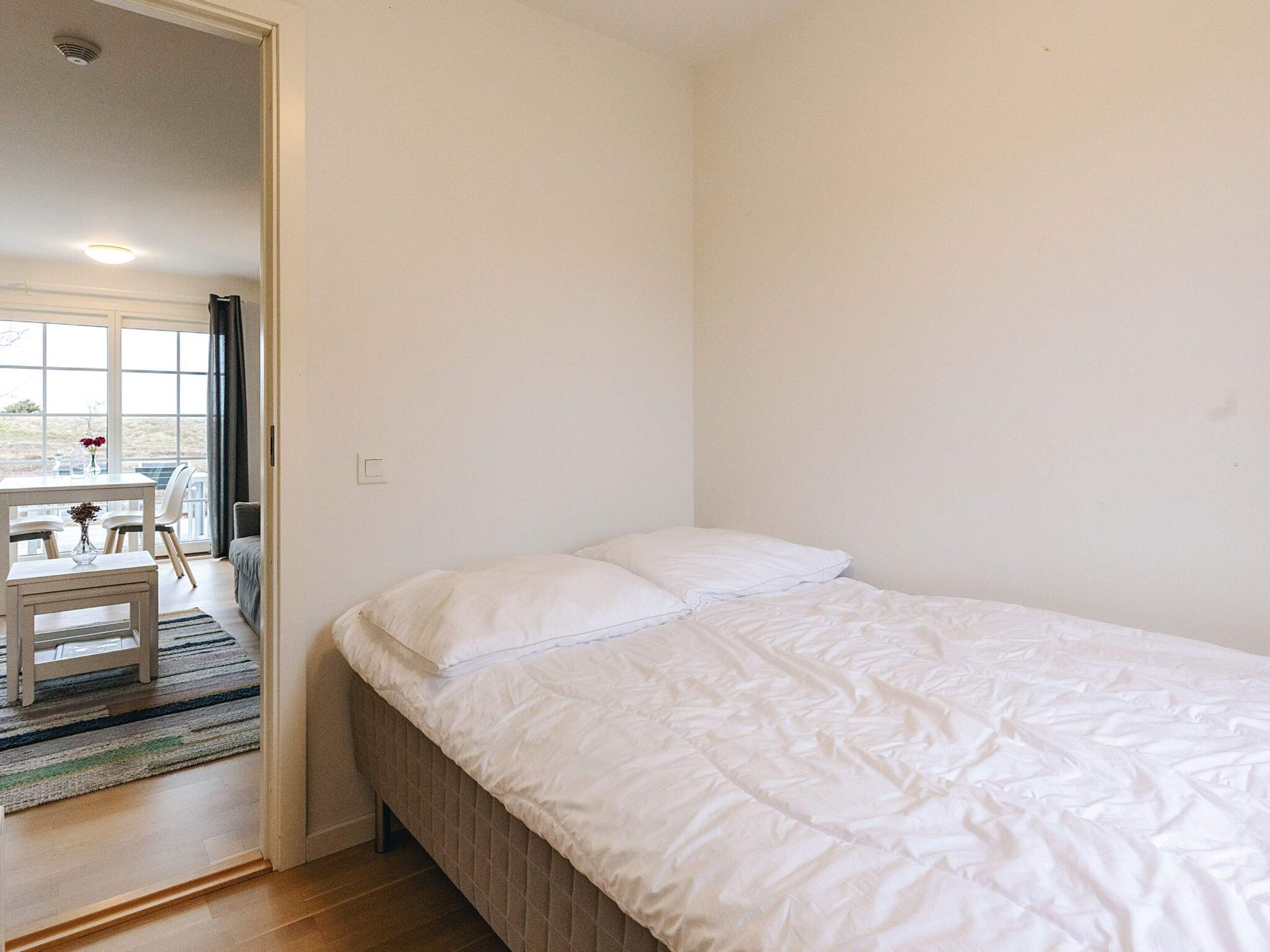 A bedroom with a bed, a window, and a dining area with a table and chairs.
