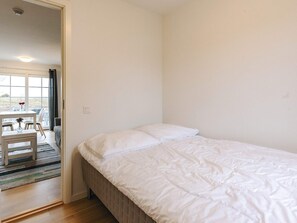 A bedroom with a bed, a window, and a dining area with a table and chairs. - 4 Star Holiday Home in Laeso (Læsø)