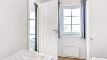 Un dormitorio con ventana, radiador y cama.