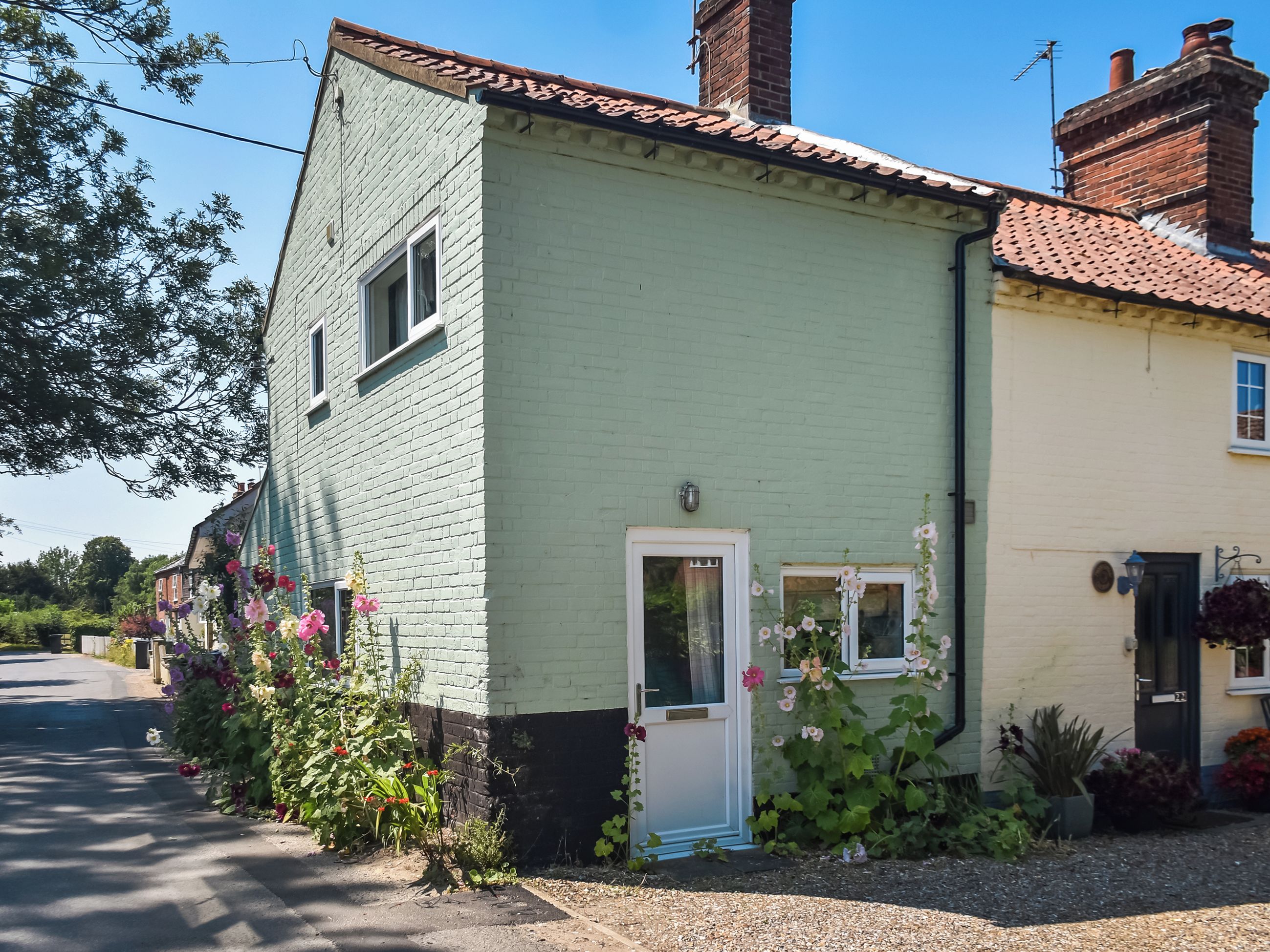 A two-story house with a green facade, a white door, and a small window.